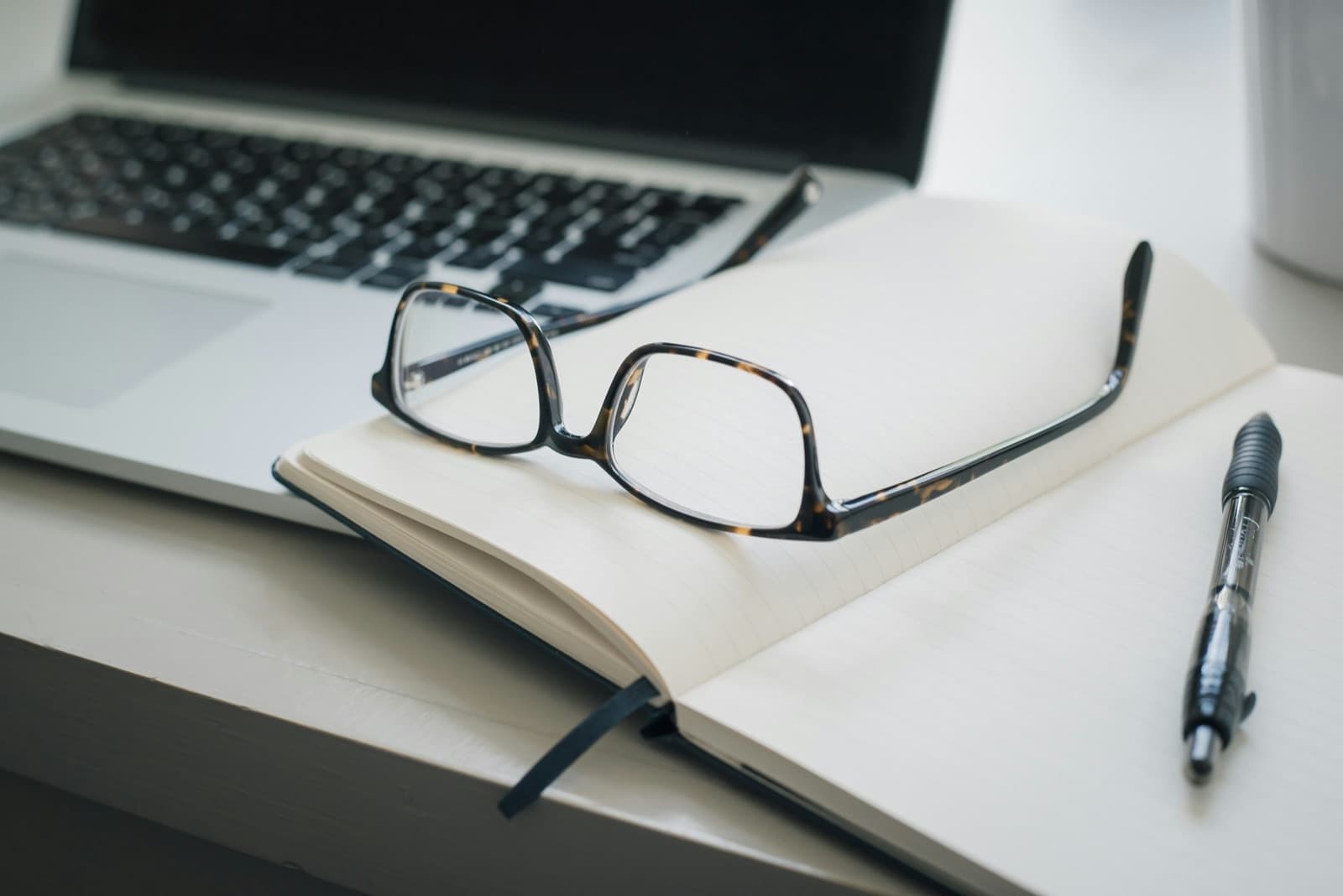 A laptop, open notebook, and reading glasses — secure telehealth therapy with Daybreak Therapy